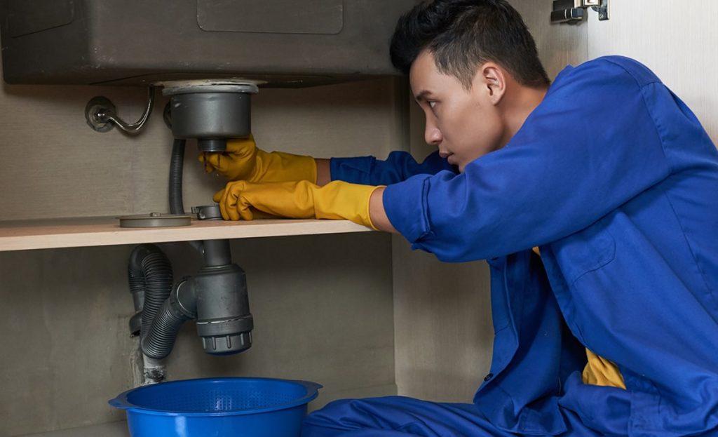 Plumber Blue Overalls Clearing Blockage Drain