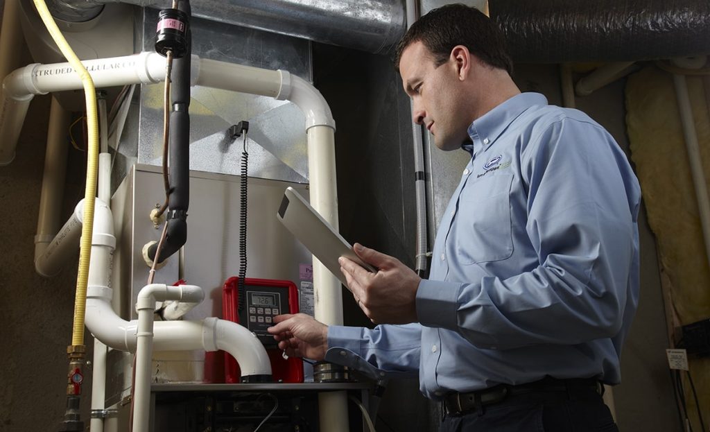 Technician Tuning A Furnace And Checking Tablet